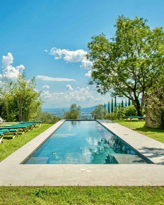 Piscina privata di Villa Di Valgiano con lettini sul prato e vista sulle colline di Lucca.