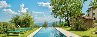 Piscina privata di Villa Di Valgiano con lettini sul prato e vista sulle colline di Lucca.