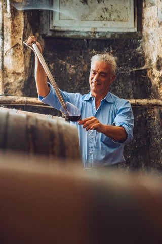 Un uomo preleva un campione di vino e lo versa in un bicchiere nella cantina della Tenuta di Valgiano.