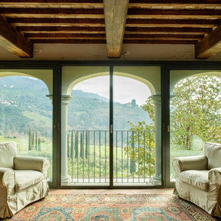 Poltrone davanti alle vetrate ad arco del soggiorno, con vista sui vigneti e sulle colline di Valgiano