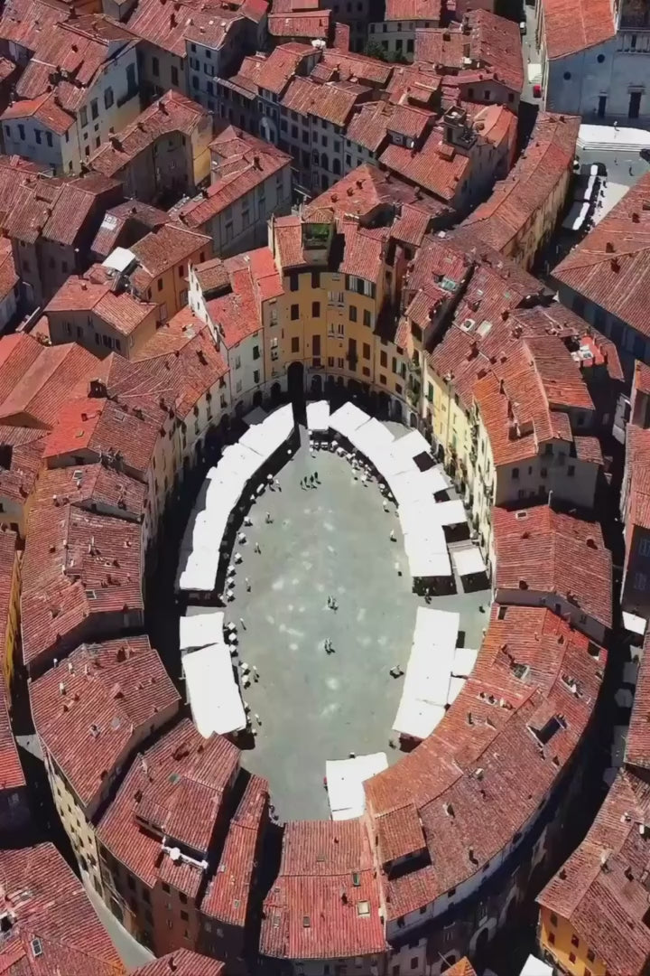 Riprese aeree del centro storico di Lucca, con Piazza dell’Anfiteatro e i tetti della città.